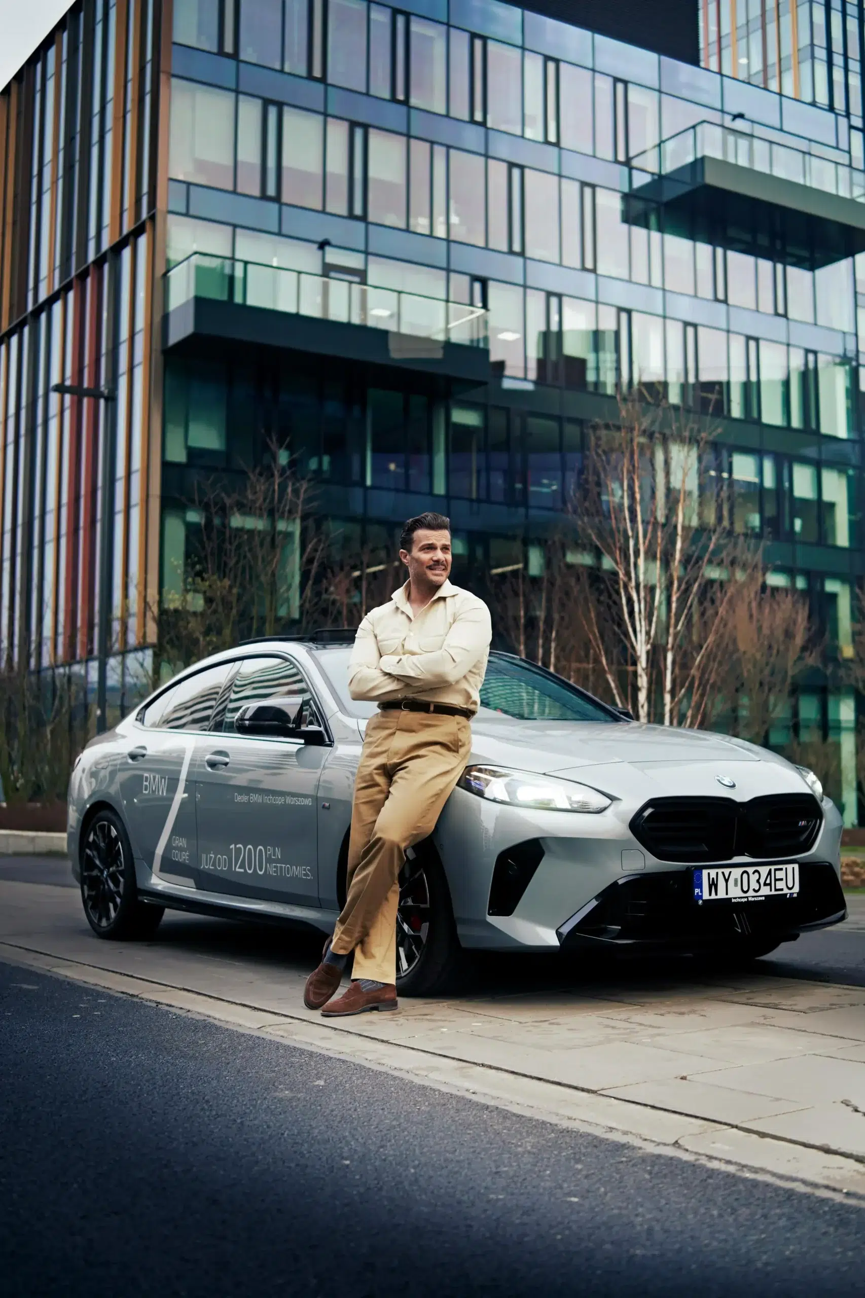 Man beside a silver BMW outside a modern building